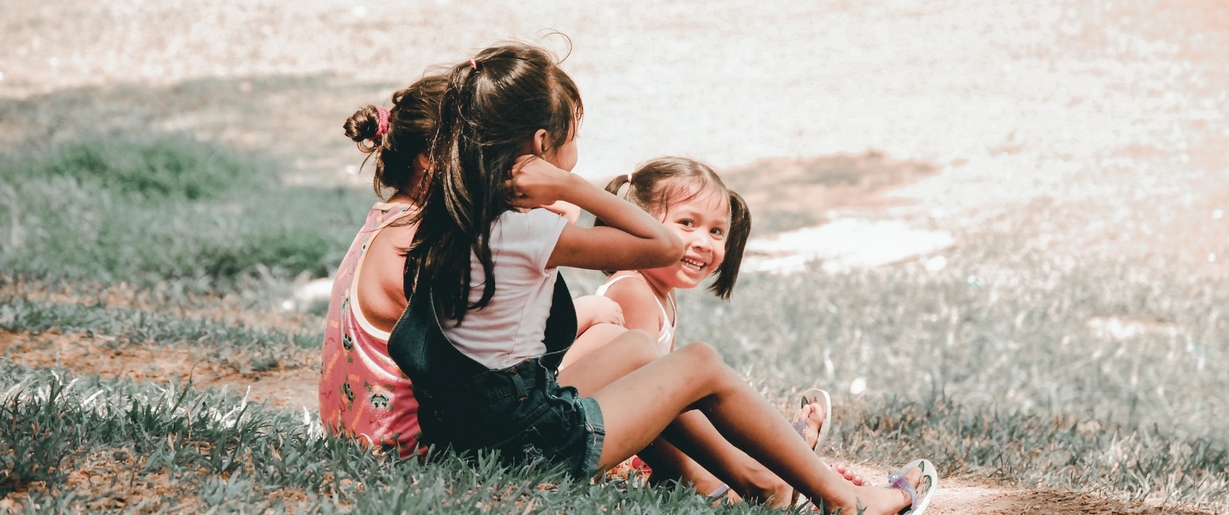 Earth Day is a good time to begin encouraging kids to get curious about the great outdoors. Three children seated in grass.