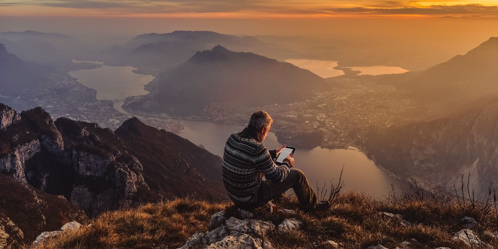Man reading ebook over cliff