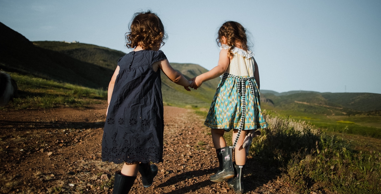 Teach children the importance of treading lightly on the Earth by always setting a great example of how it's done. Two children walking outdoors and holding hands.