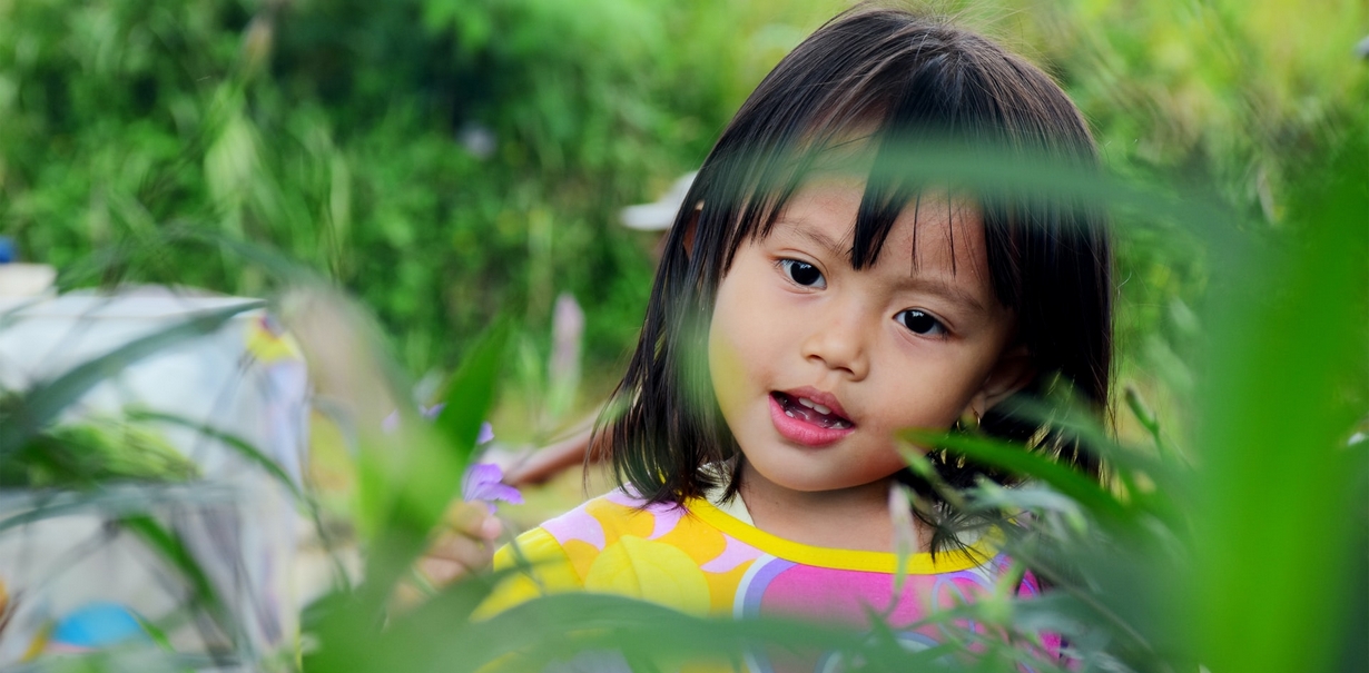 With your help, nature can teach a child the subtleties of colors. Small child admiring a purple flower.